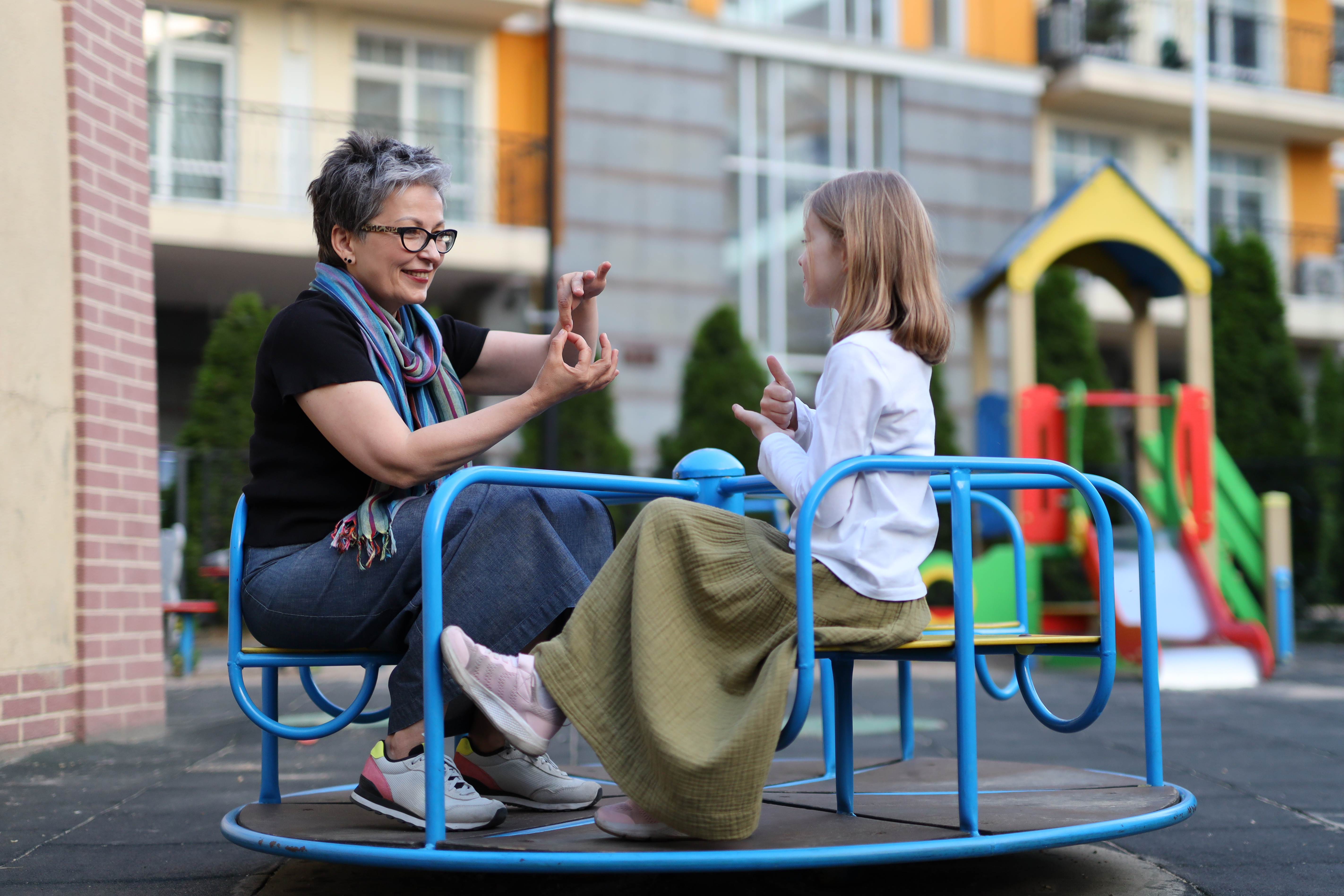 Educational therapist and student seated on the school playground as they practice sign language. 