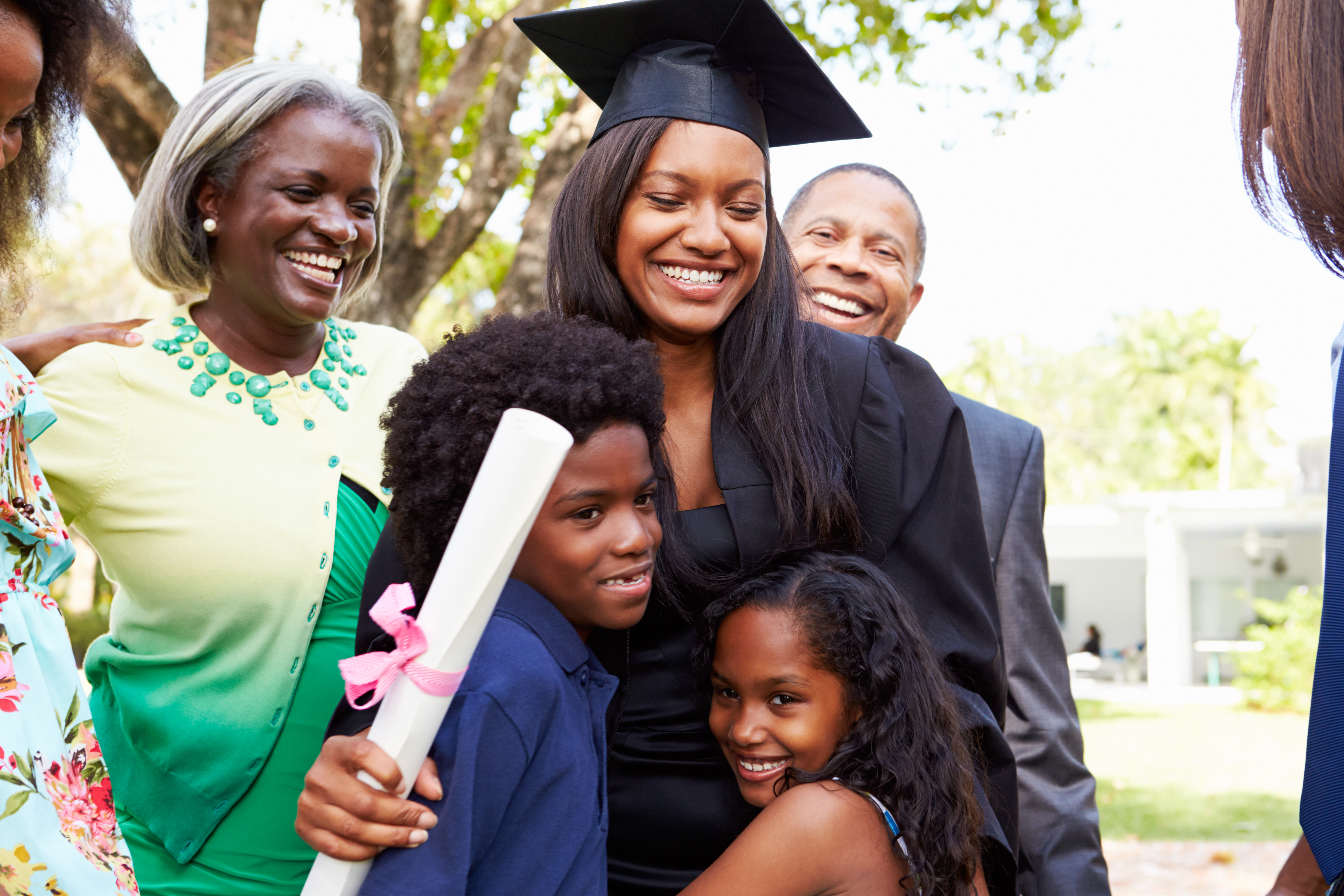 An african american woman celebrates her graduation while hugging her family