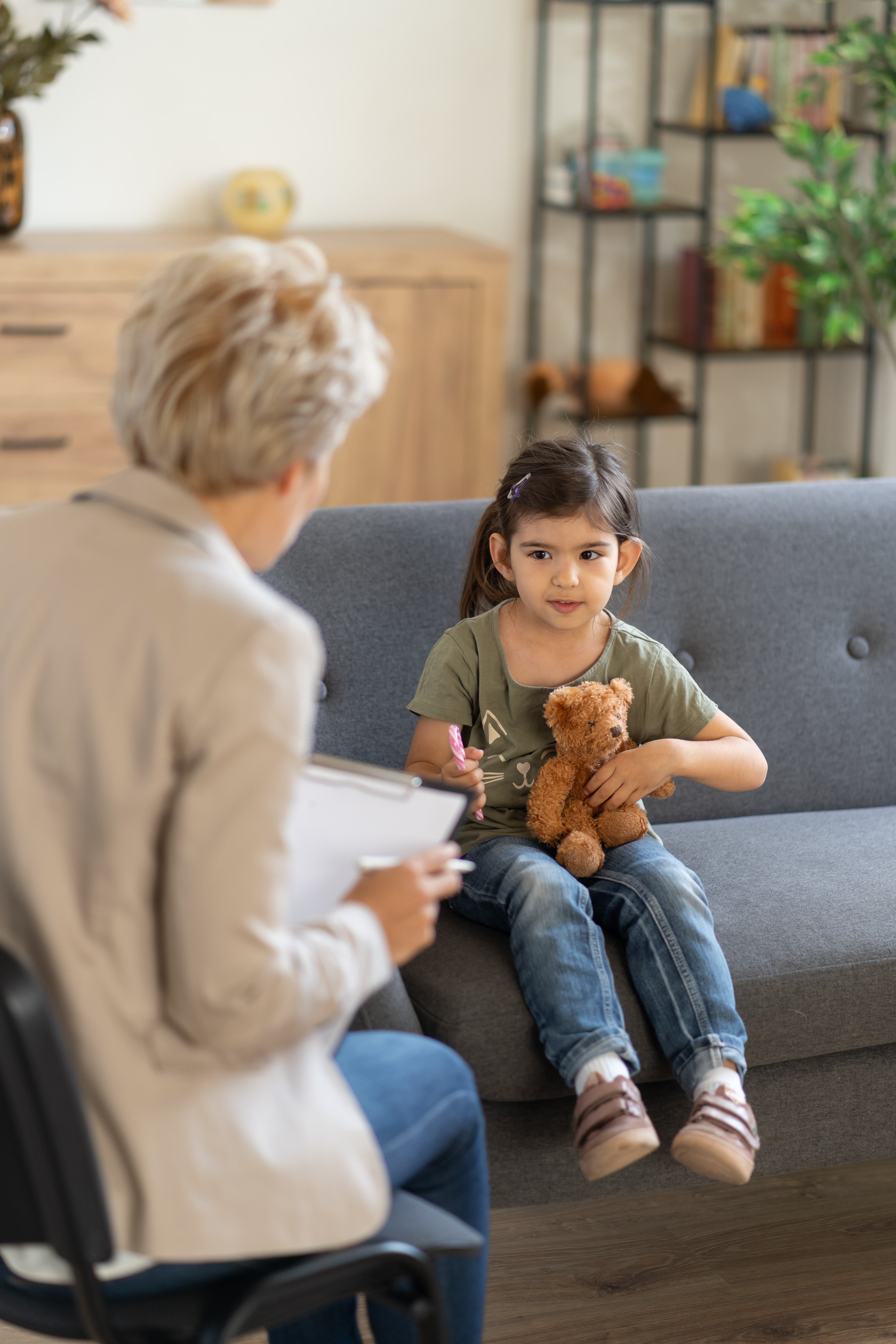 A cheerful child communicates with a psychologist who is making notes in an interactive session discussing child psychology