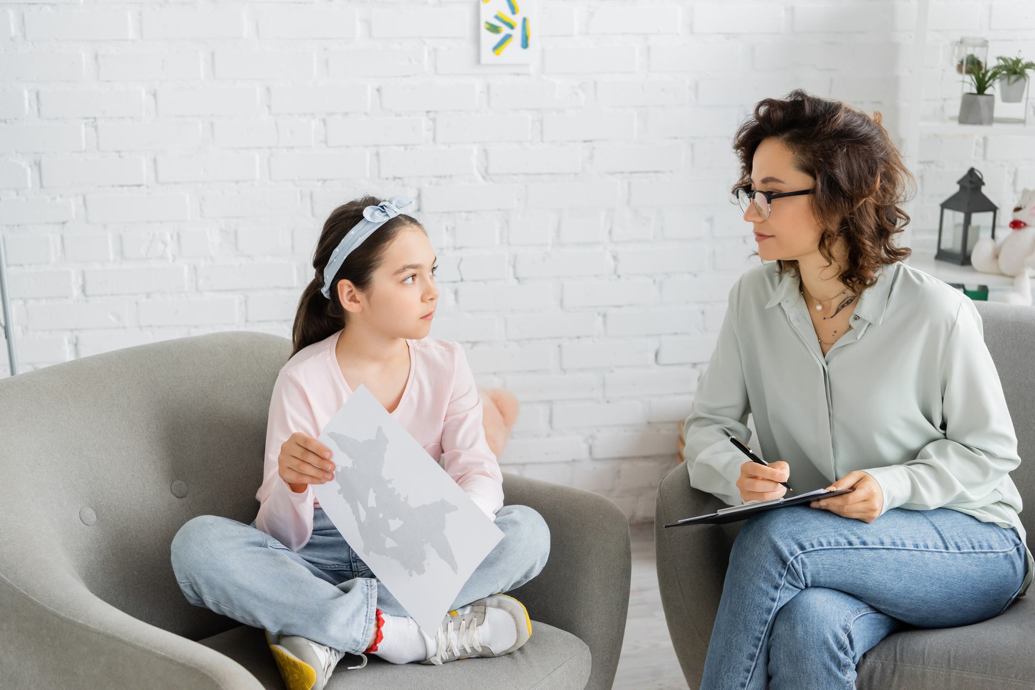 A female therapist and her young patient look at each other during therapy session.