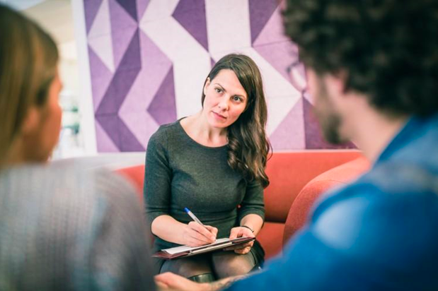 A marriage and family therapist takes notes during a session with a couple