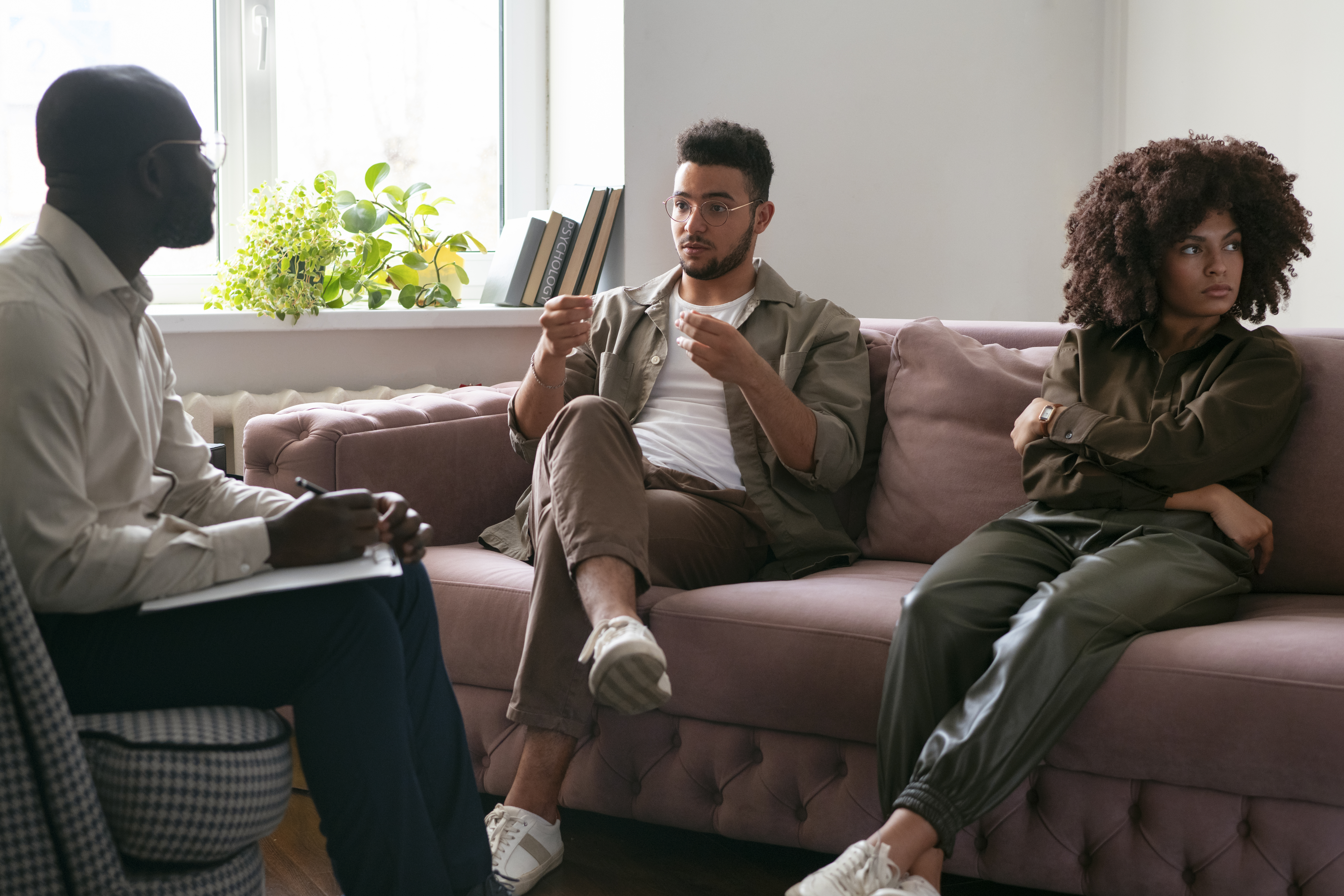 A private practice therapist is seated across from a couple seated on a couch expressing their feelings.