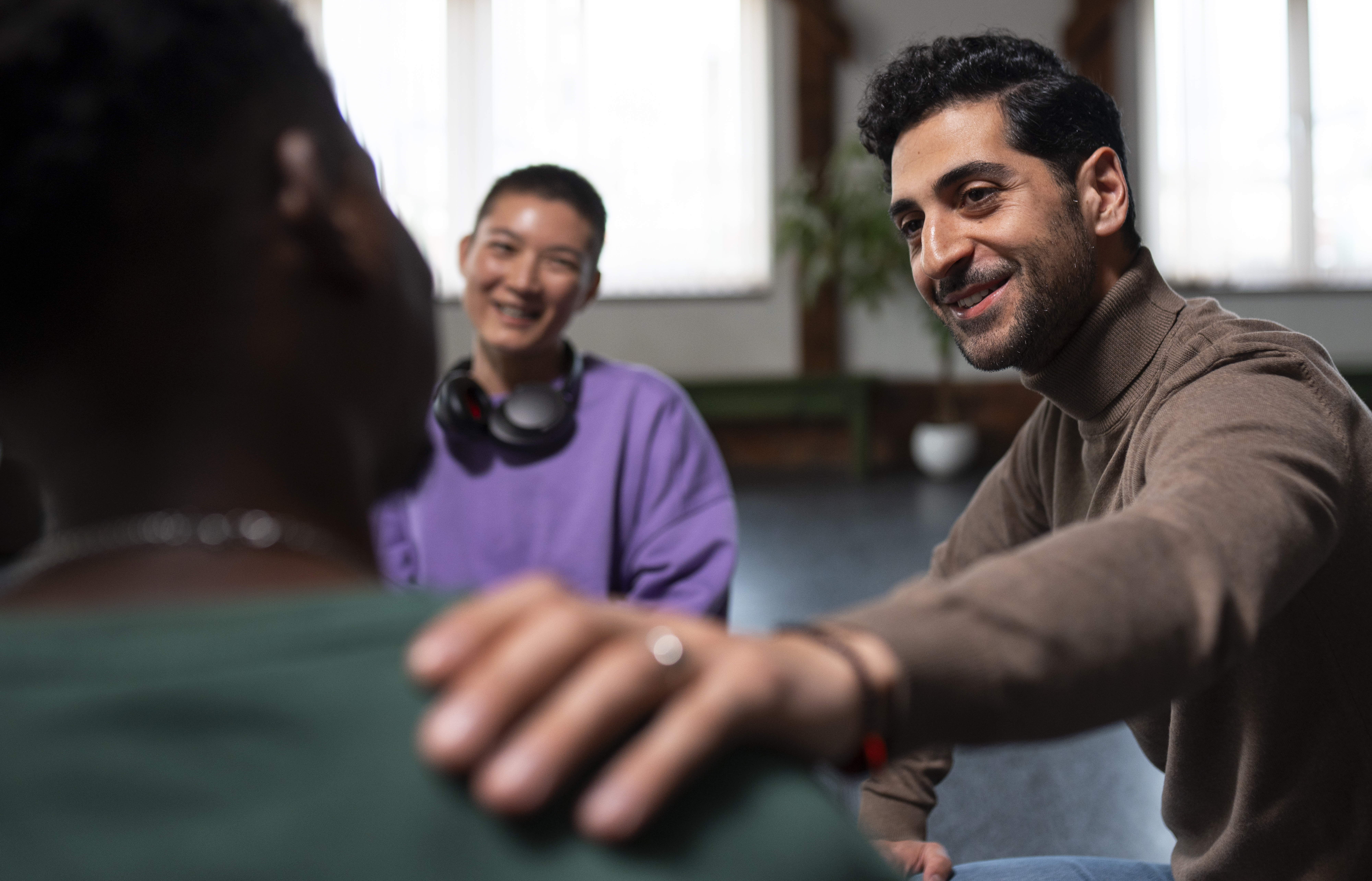 A mental health advocate reassuring a group therapy member by placing a hand on their shoulder.