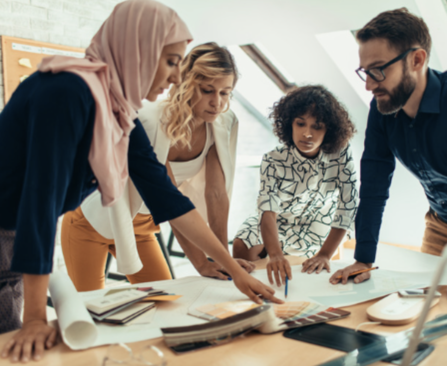 Four people standing at a desk and working.